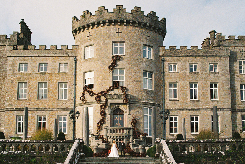 Bride and groom stand on the steps of Markree Castle, framed by its tall windows and round tower