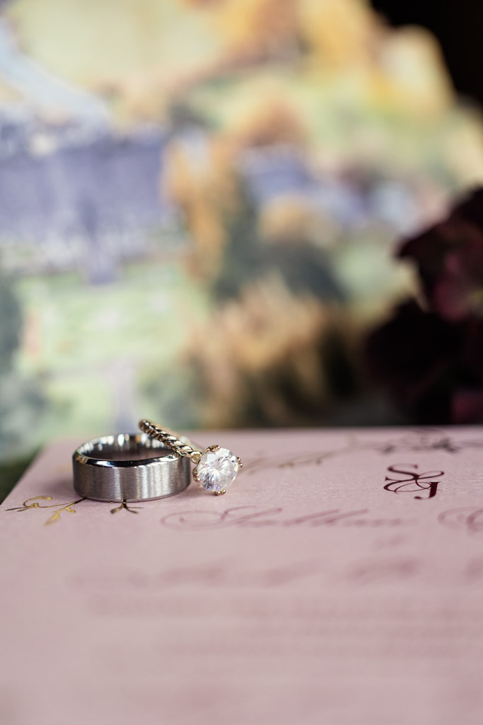 A diamond ring and a silver band rest on a pink floral card with a blurred background for Markree Castle wedding celebration