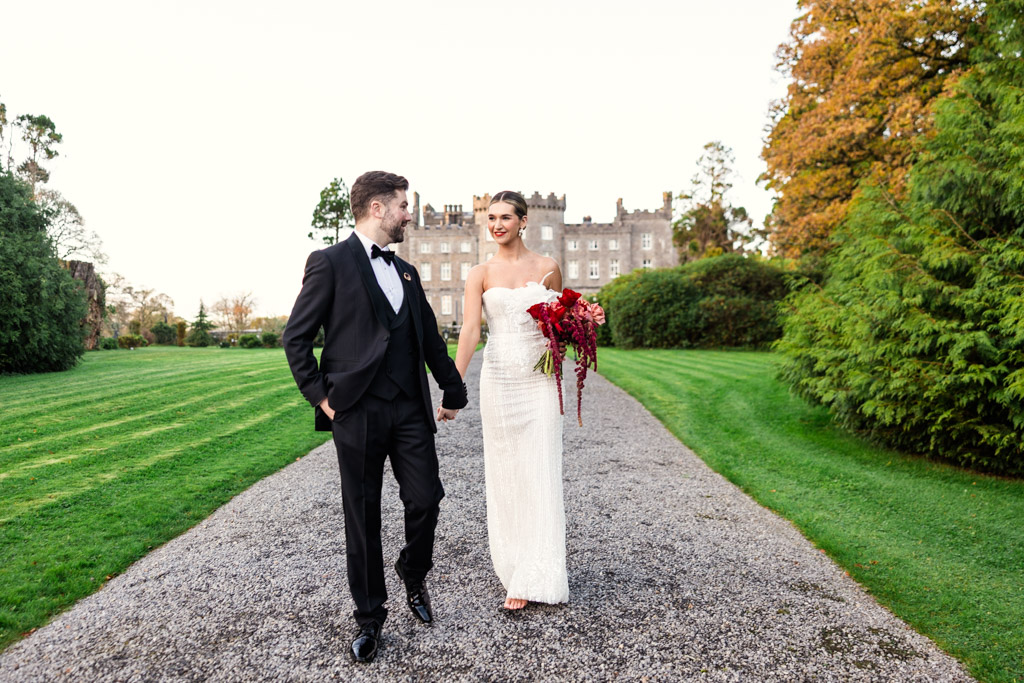 Bride and groom walk hand in hand along a path outside Markree Castle
