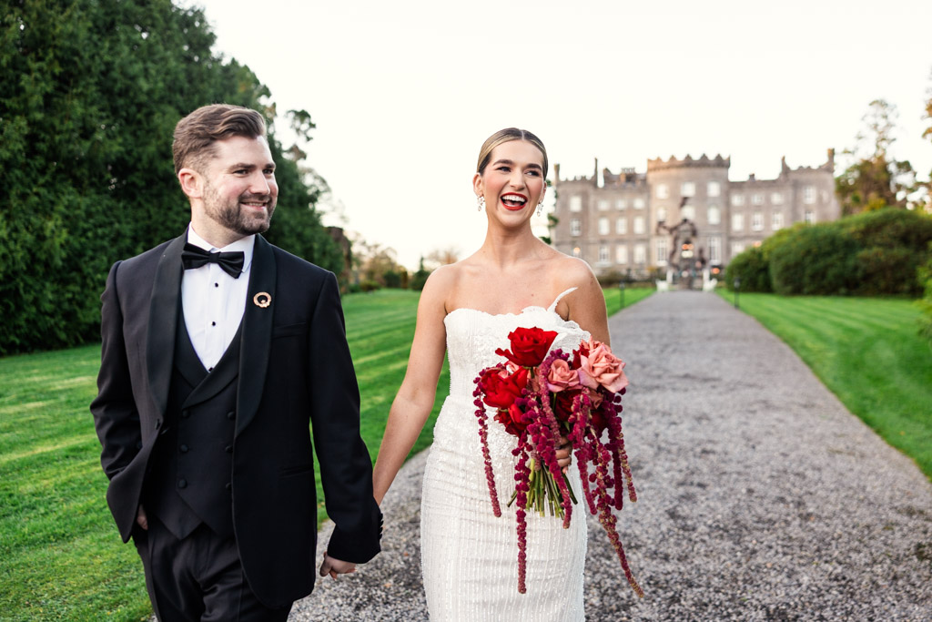 Bride and groom smiling and holding hands outdoors, with Markree Castle in the background