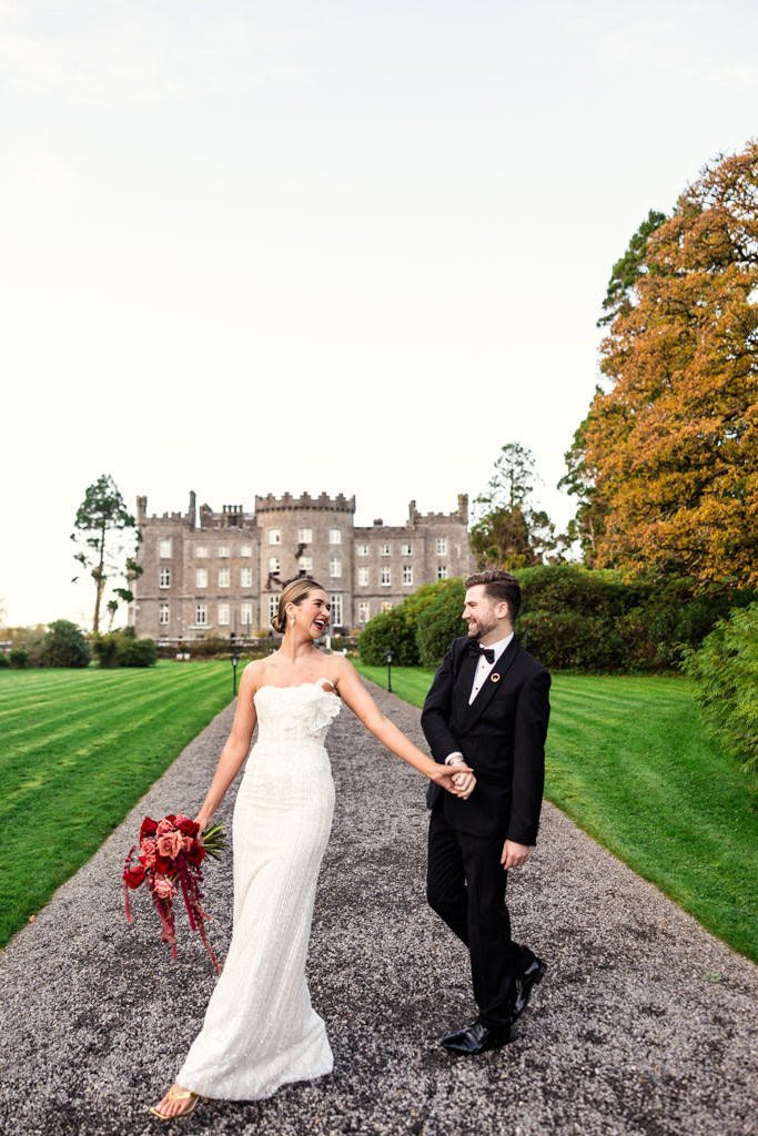 Bride and groom smiling and holding hands, walking outside Markree Castle