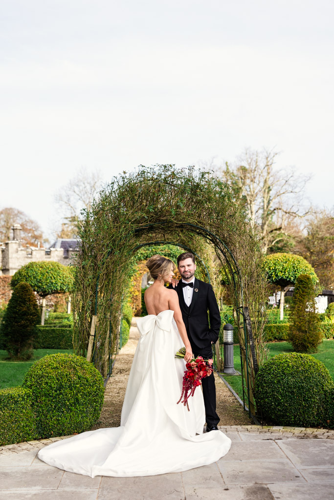 Bride and groom stand under a garden archway at Markree Castle