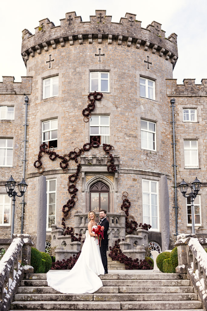 Portrait of bride and groom standing on stone steps in front of Markree Castle