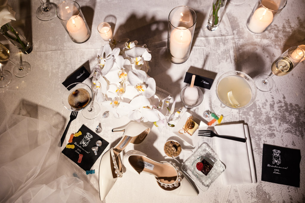 Bride's shoes, veil, and bouquet on a table with candles, desserts and custom napkins for Four Seasons Chicago wedding celebration