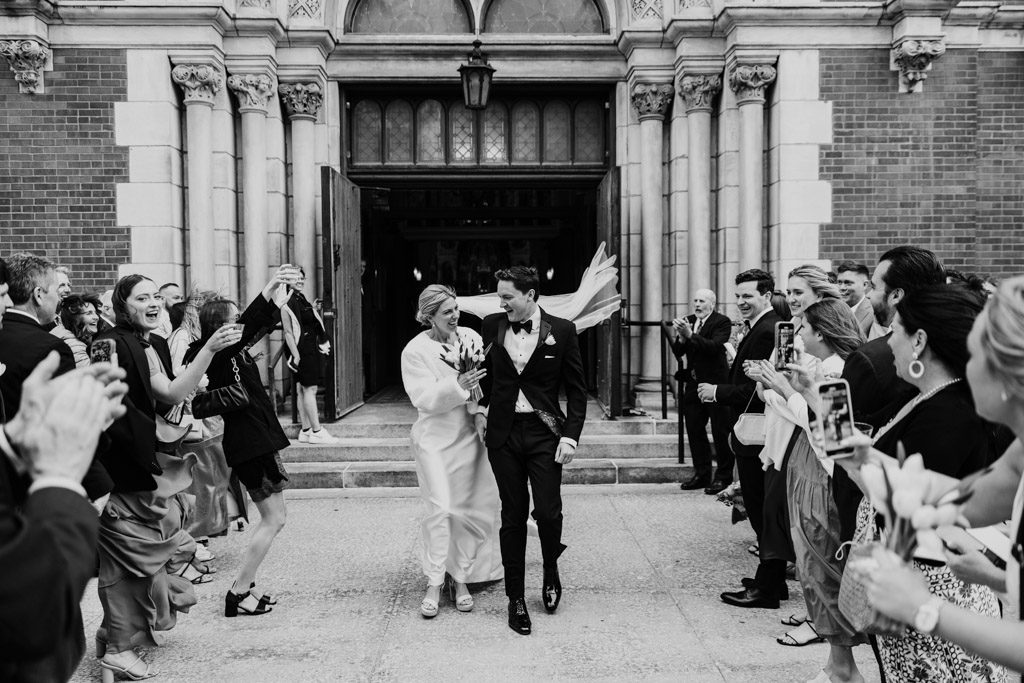 Happy newlywed couple exits St. Michael's Church in Old Town as guests cheer and take photos