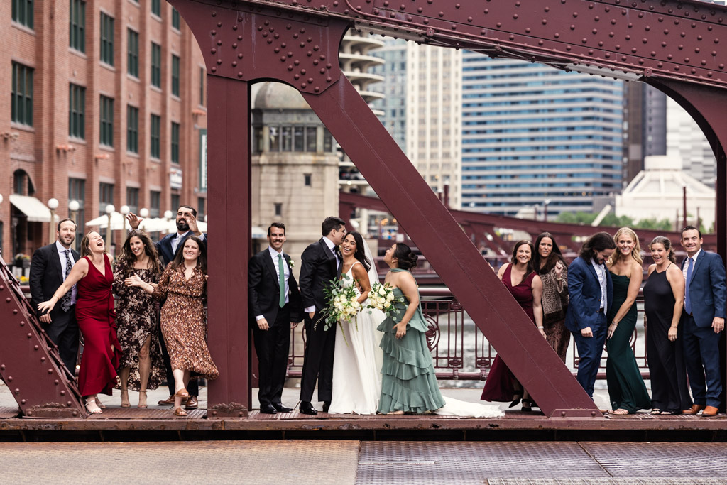 Bride and groom pose and celebrate with their friends on the LaSalle Street Bridge with tall buildings in the background