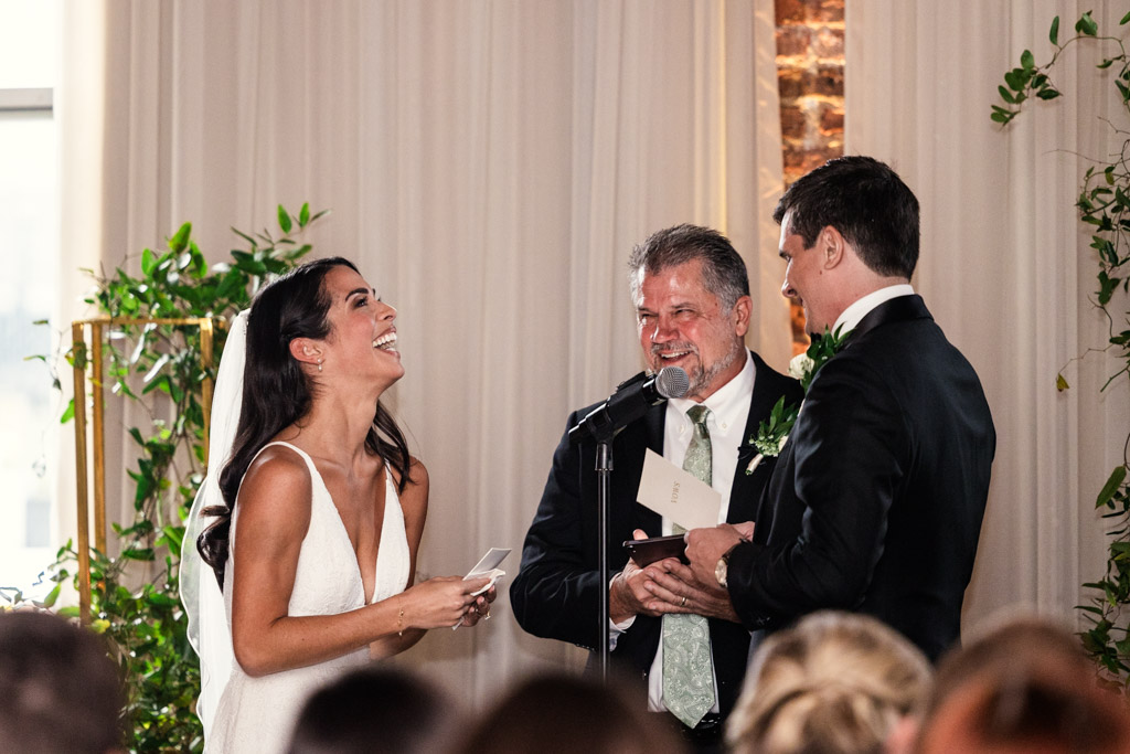 A bride and groom laugh with an officiant during their Bottom Lounge wedding ceremony