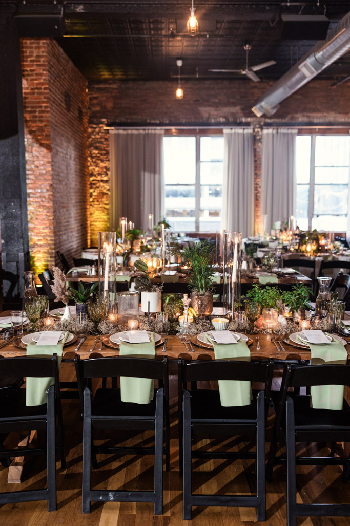 Guest tables set with greenery, candles, glassware, and napkins for a Bottom Lounge wedding