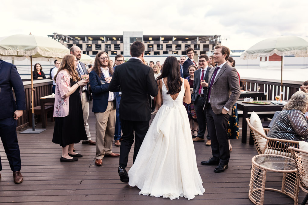 Bride and groom chat with guests at their Bottom Lounge wedding during cocktail hour on a wooden deck