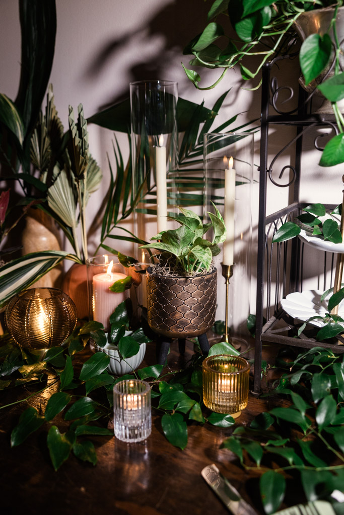 Candles, glass votives, and potted plants on a wooden table with leafy greenery and candlelight for Bottom Lounge wedding reception