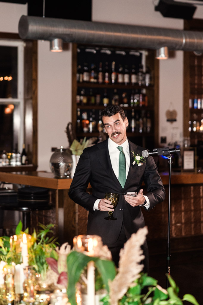 Best Man in a suit with a green tie gives a speech at a Bottom Lounge wedding reception