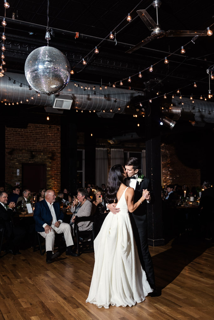 Newlyweds share their first dance under a sparkling disco ball at their Bottom Lounge wedding reception