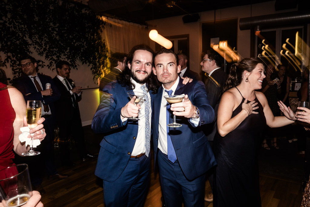 Two guests in suits pose with drinks at Bottom Lounge wedding reception