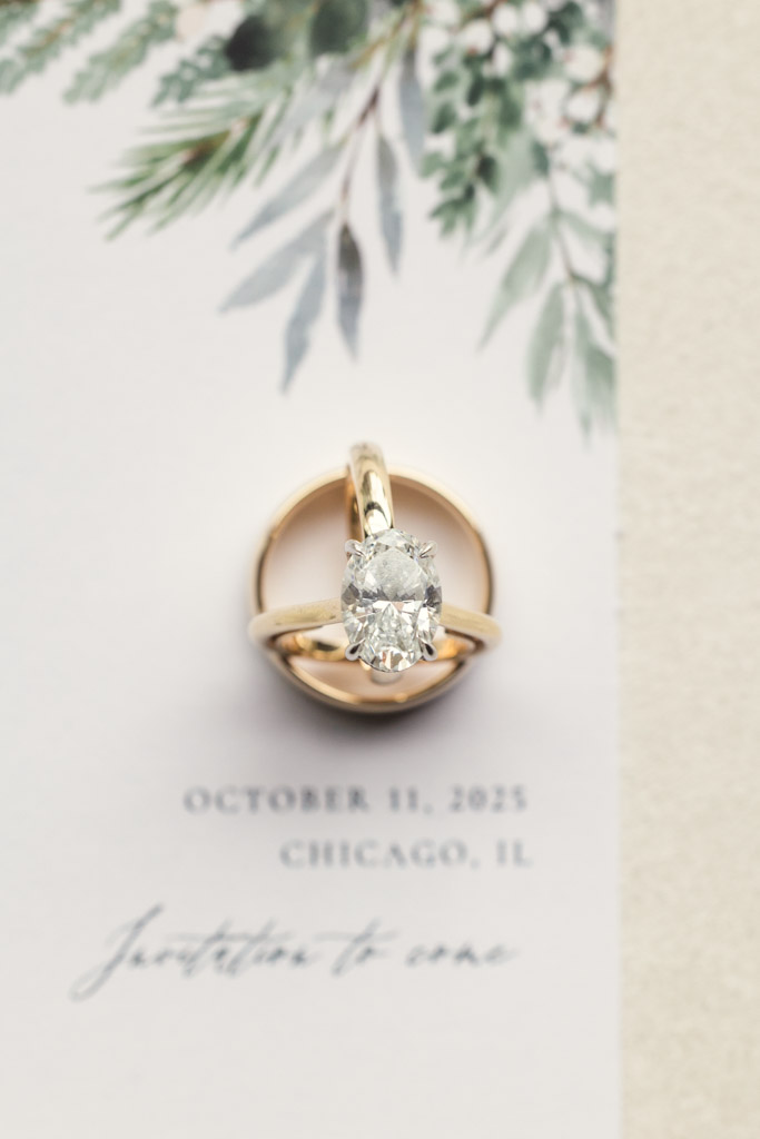 An engagement ring and wedding band rest on a wedding invitation for Bottom Lounge wedding in Chicago
