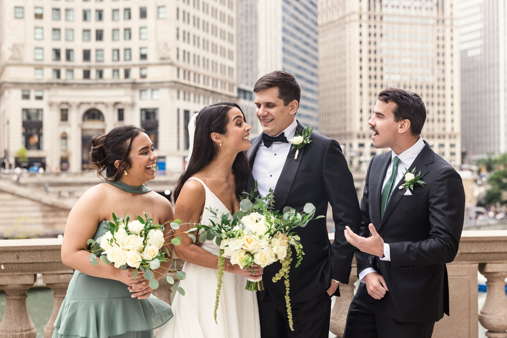 Bride and groom laughing with bridesmaid and groomsman near the river in downtown Chicago