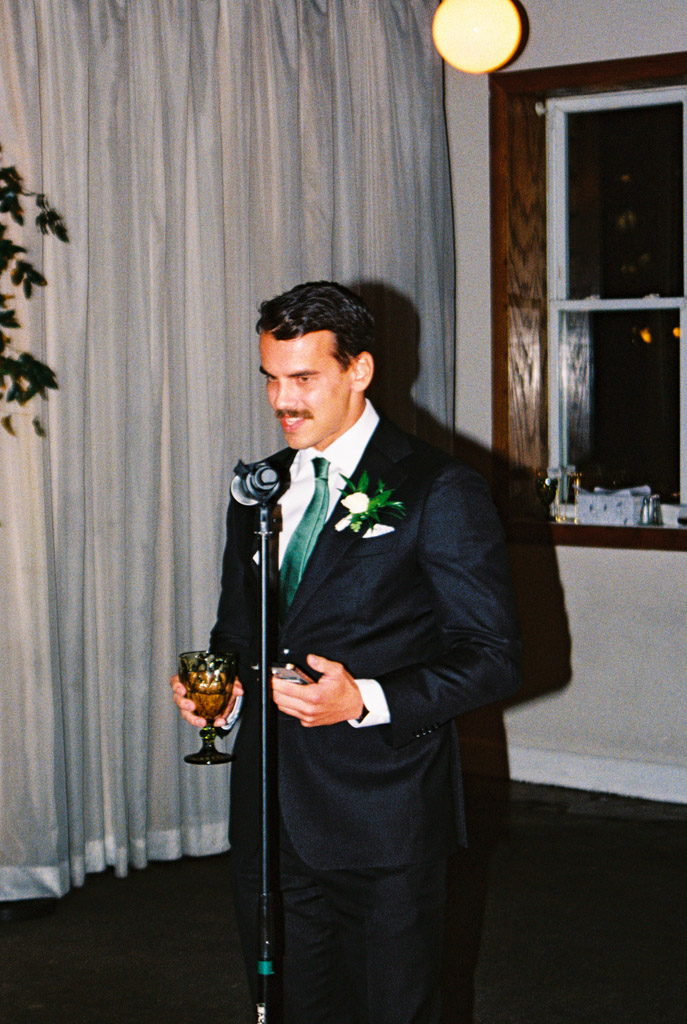 Film photo of Best Man in suit with green tie giving speech during Bottom Lounge wedding reception