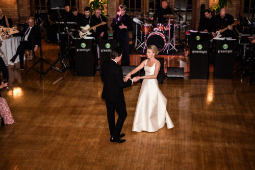 A bride and groom share their first dance on a wooden floor with a live band playing behind them, capturing a magical moment worthy of the Best of 2025 celebrations.
