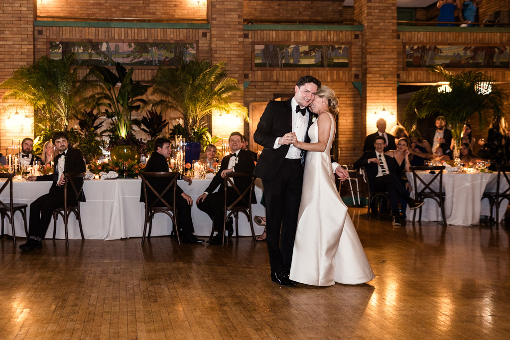 A bride and groom share their first dance at their Cafe Brauer wedding reception, surrounded by guests