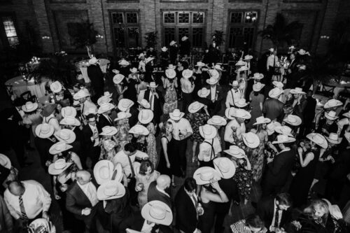 Black and white photo of dance floor at Cafe Brauer wedding reception with most guests wearing white cowboy hats, seen from above