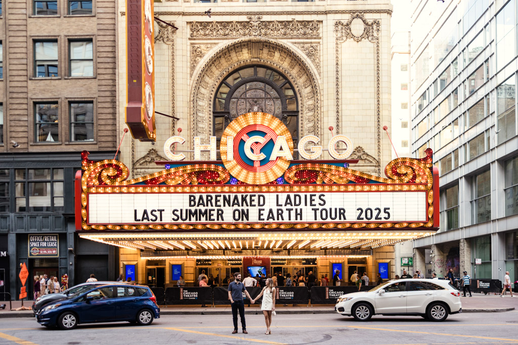 Engaged couple holds hands in front of the Chicago Theatre marquee