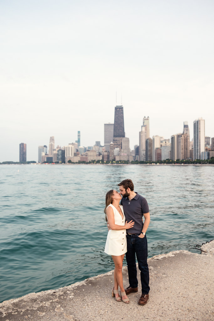 Couple kisses by the waterfront at North Avenue Beach during their Chicago summer engagement session, with the city skyline in the background