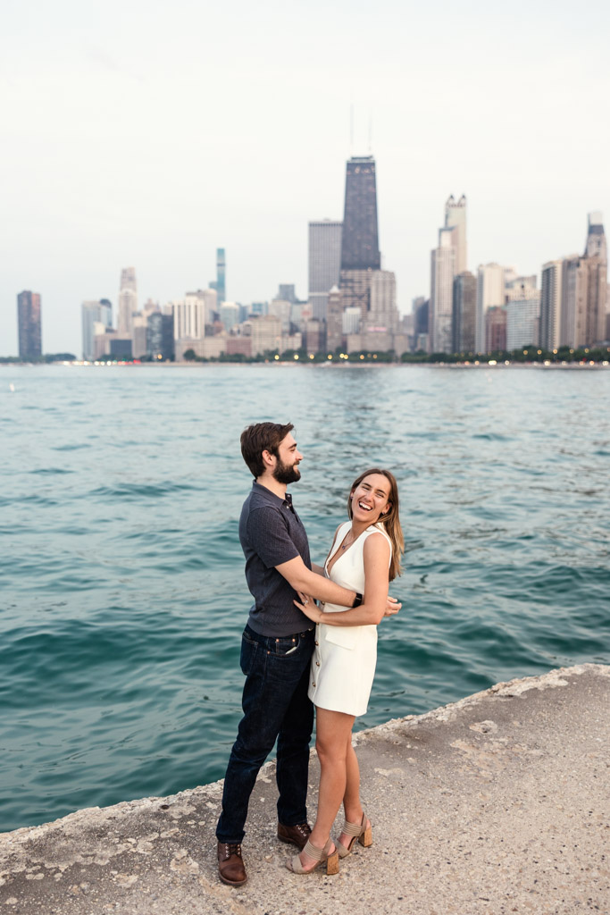 Candid photo of happy engaged couple by Lake Michigan with Chicago skyline in the background