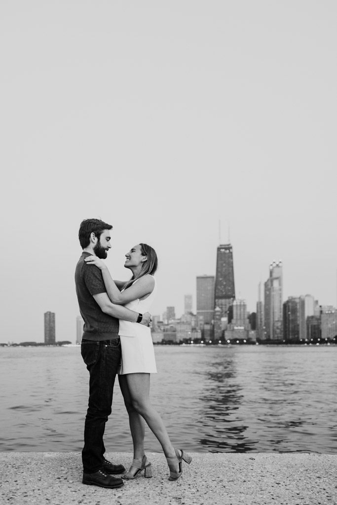 Black and white photo of couple by the Lake Michigan waterfront with the Chicago skyline in the background