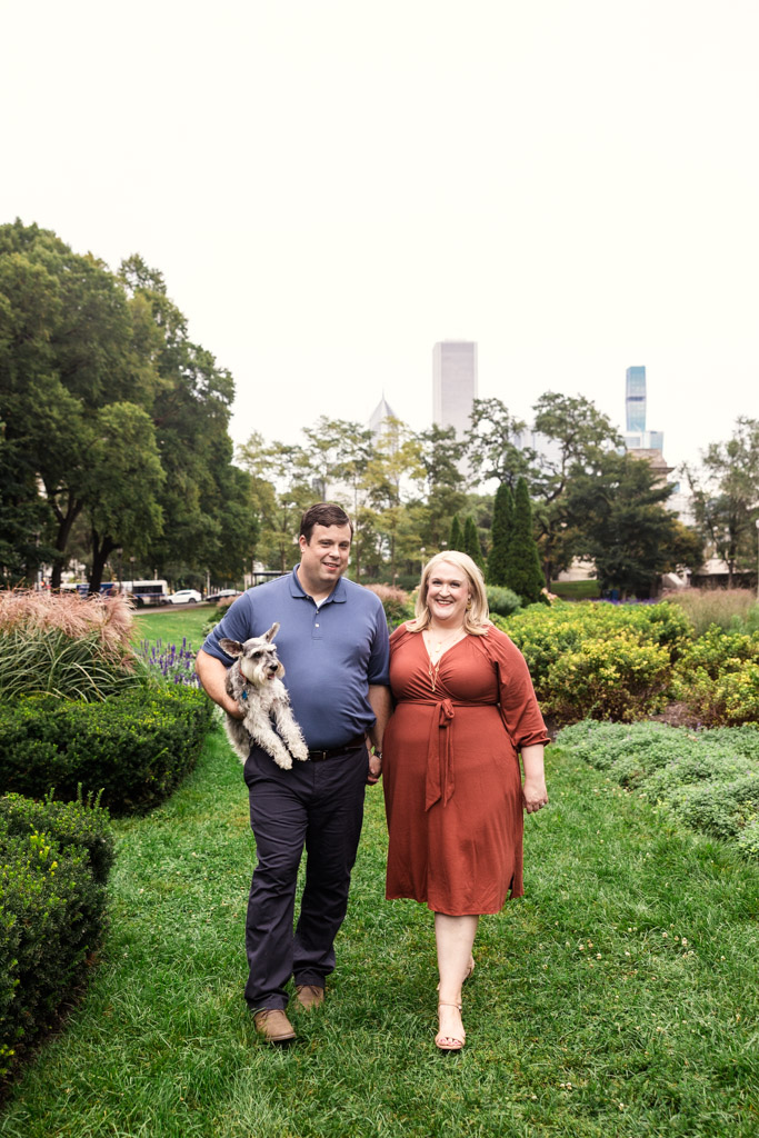 A man and woman walk through Grant Park in the South Loop; the man holds a small dog