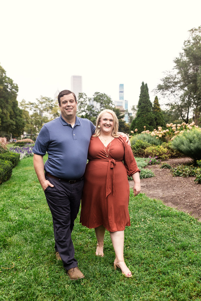 Happy couple walks arm-in-arm through a green garden in Grant Park during their South Loop engagement session