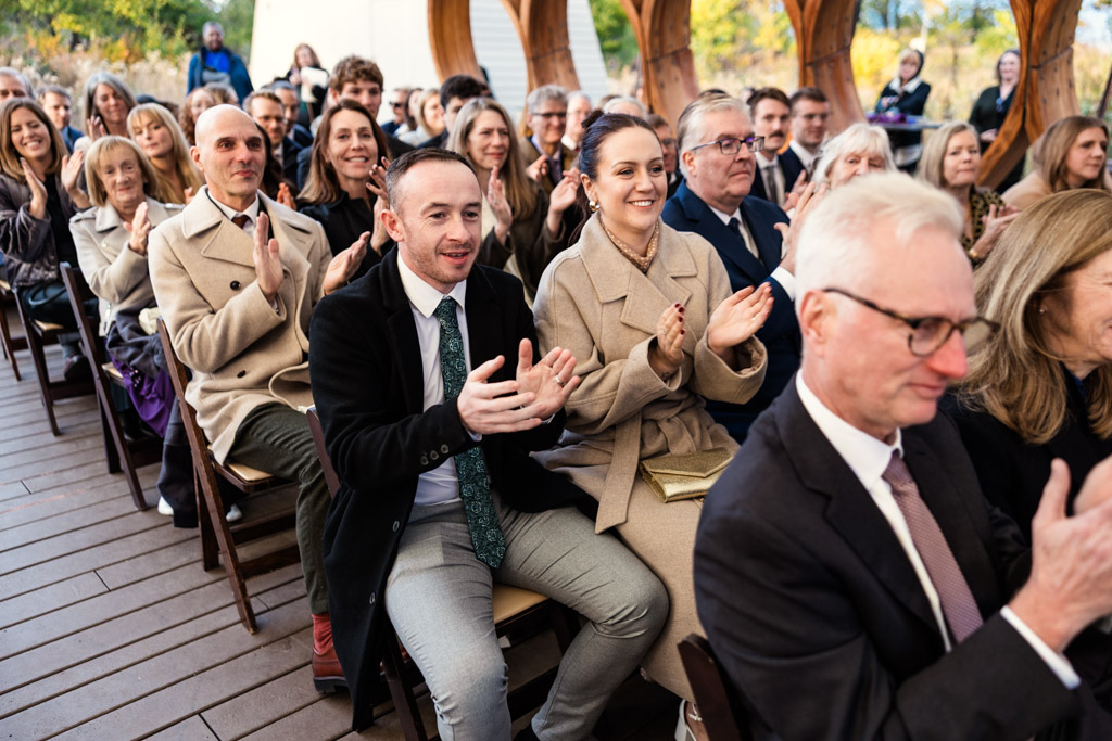 Guests smiling and clapping during wedding ceremony under the Lincoln Park Honeycomb