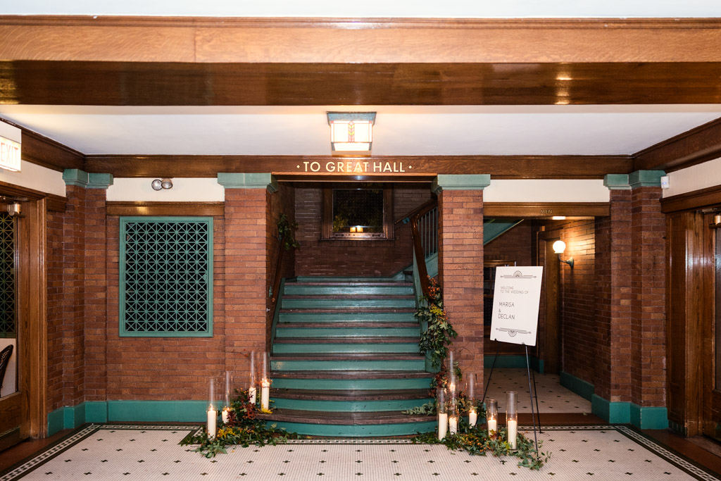 Brick stairway with green trim, candles, and foliage, leading to Cafe Brauer wedding.reception space