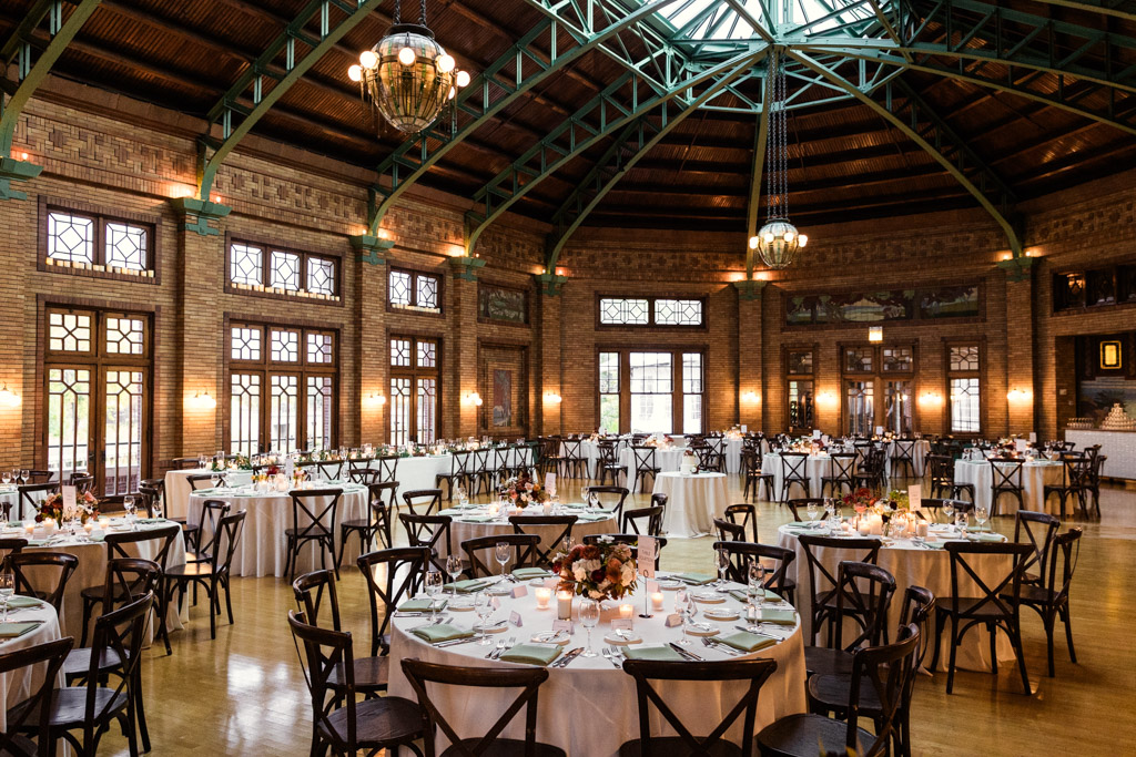 Cafe Brauer wedding reception space with round tables under a large skylight and warm lighting