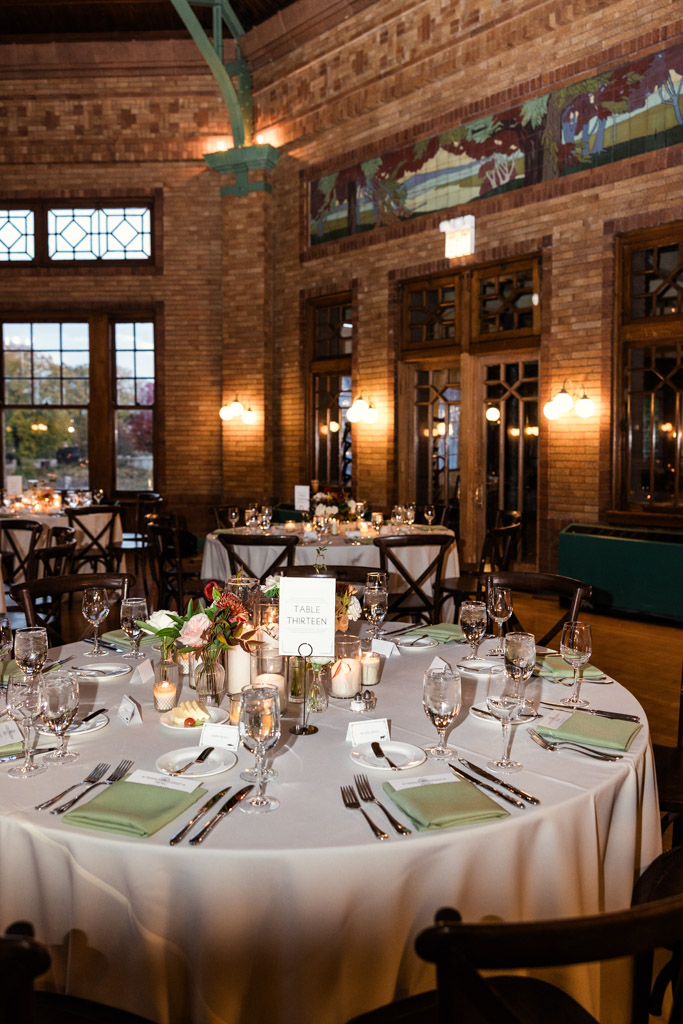 Round guest table set for a wedding reception in the warmly lit, historic brick venue of Cafe Brauer