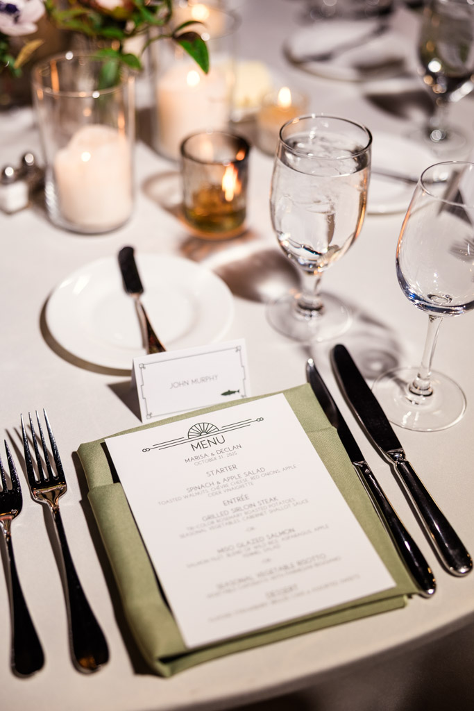 Guest place setting with menu, cutlery, water glass, candles, and a name card for a Cafe Brauer wedding celebration