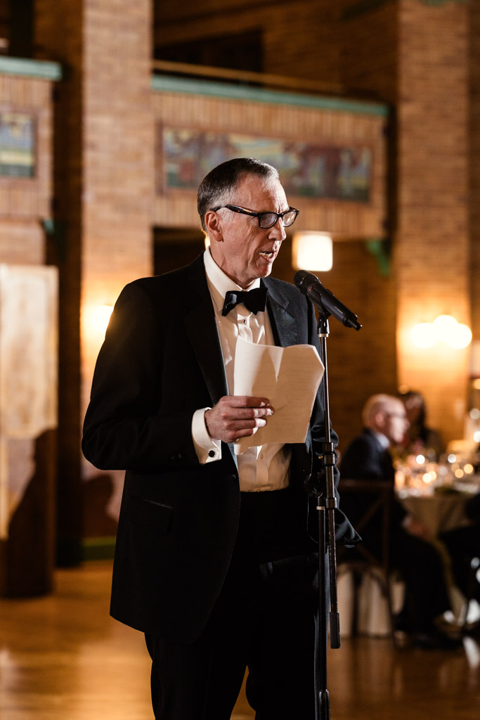 Bride's father in a tuxedo gives a speech during wedding reception at Cafe Brauer in Lincoln Park, Chicago