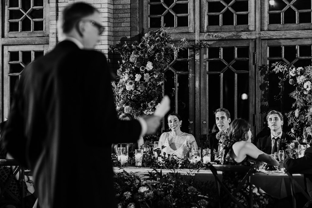 Bride and groom listen to bride's father give a speech during their Cafe Brauer wedding reception
