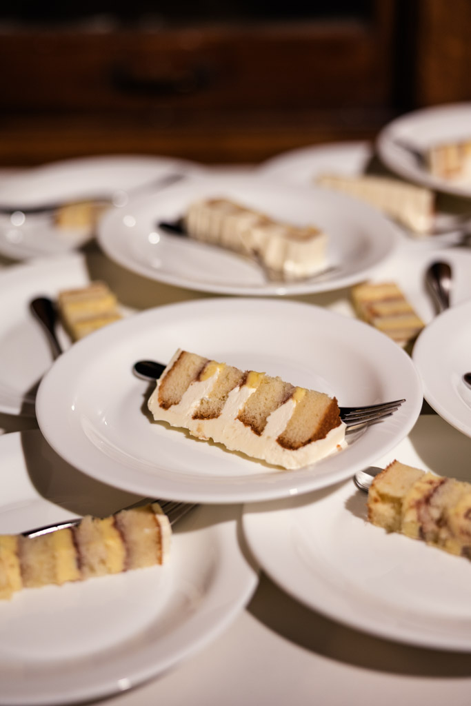 Slices of layered wedding cake on white plates on a white table for Cafe Brauer wedding reception