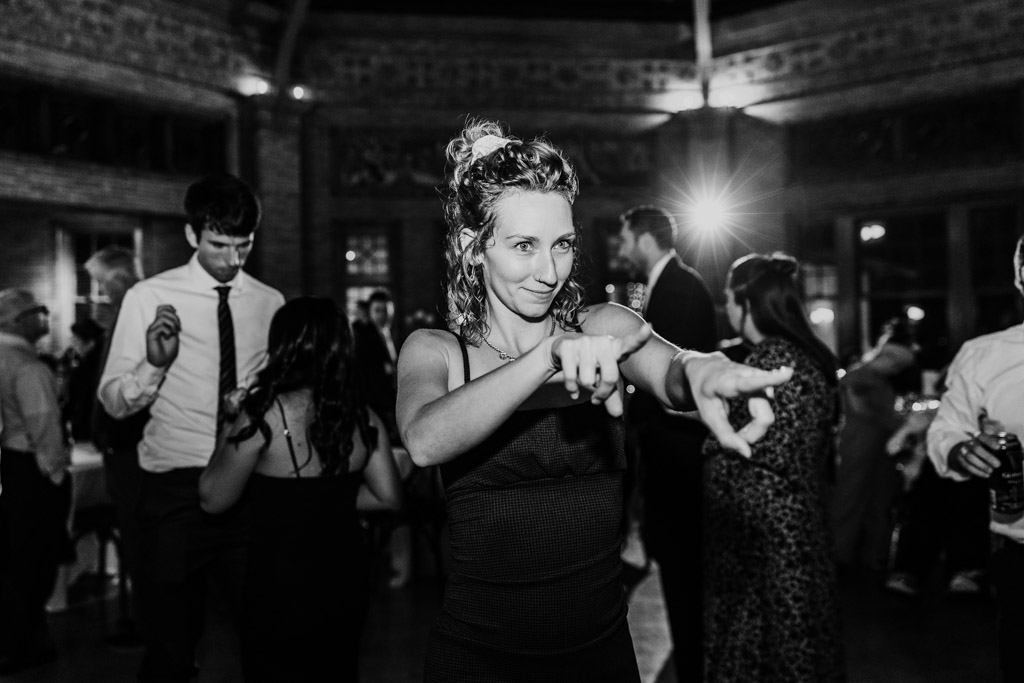 Woman in a dress dancing and pointing during Cafe Brauer wedding reception, with other guests celebrating in the background