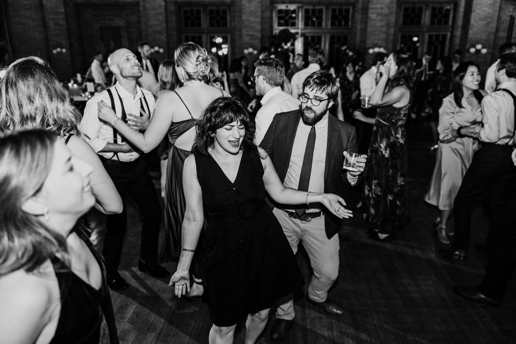 Black and white photo of guests dancing energetically at a Cafe Brauer wedding celebration