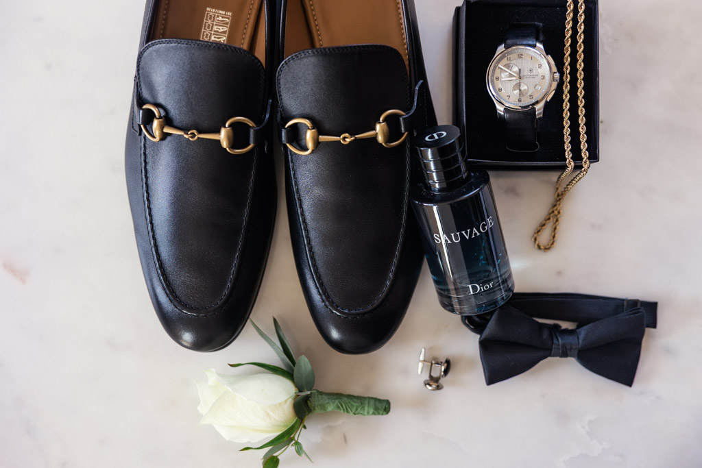 Groom's loafers, watch, Dior Sauvage cologne, black bow tie, cufflinks, and a white boutonniere for Lincoln Park Conservatory wedding