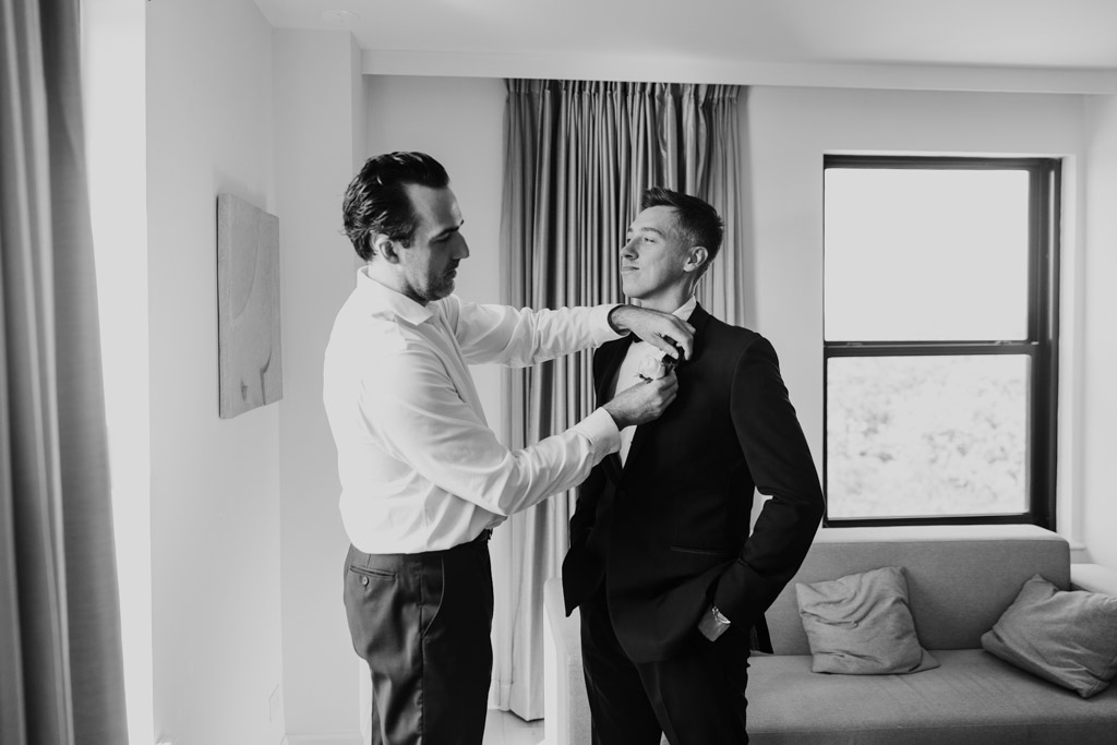 Black and white photo of Best Man helping groom with his boutonniere at Hotel Lincoln in Chicago