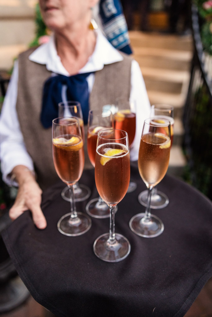 Server holding a tray with glasses of sparkling rosé, each garnished with a lemon slice—perfect for a chic Lincoln Park Conservatory wedding.