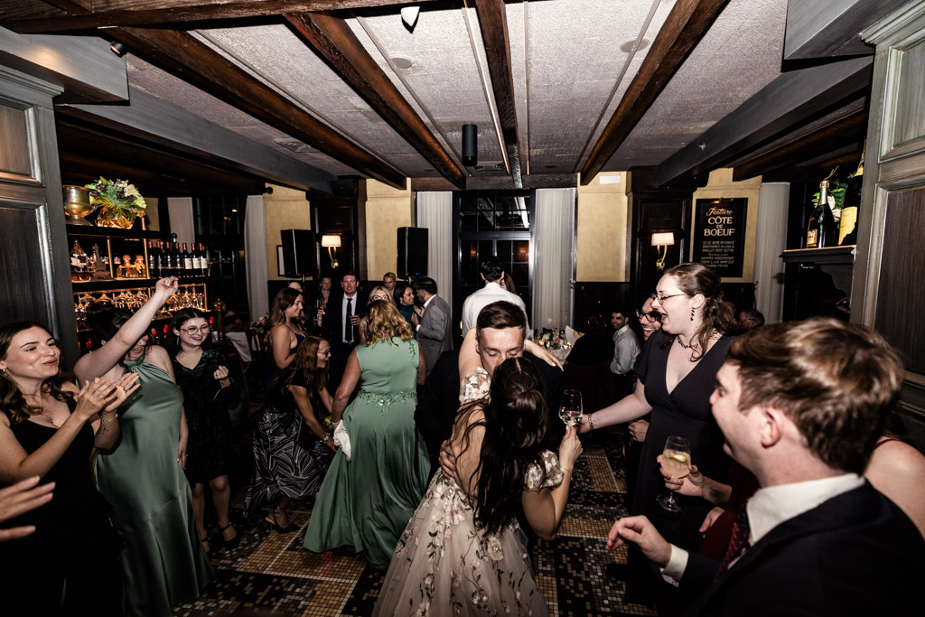 Bride and groom kiss and guests celebrate on a lively dance floor during Mon Ami Gabi wedding reception