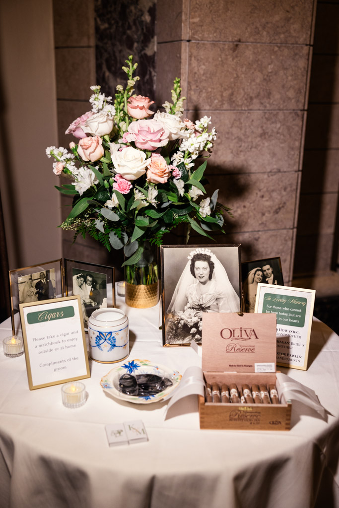 A round table with cigars, family photos, flowers, and wedding memorabilia for Mon Ami Gabi wedding reception