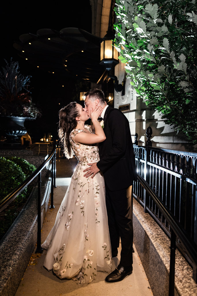 A bride and groom kiss outdoors at night during their Mon Ami Gabi wedding reception