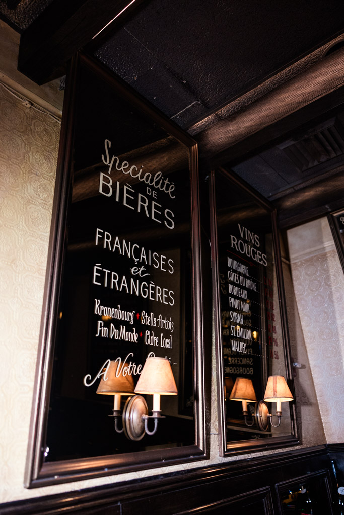 Wall mirrors with French menu writings and two small lamps below inside Mon Ami Gabi