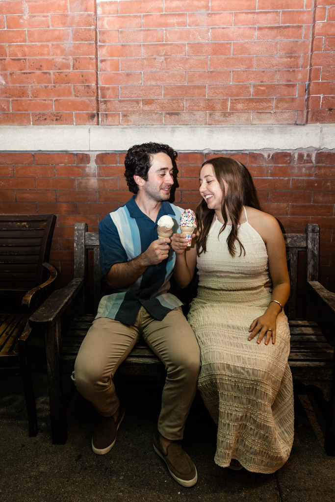 Happy engaged couple on a bench enjoying ice cream cones outside Scooters Frozen Custard in Roscoe Village at night