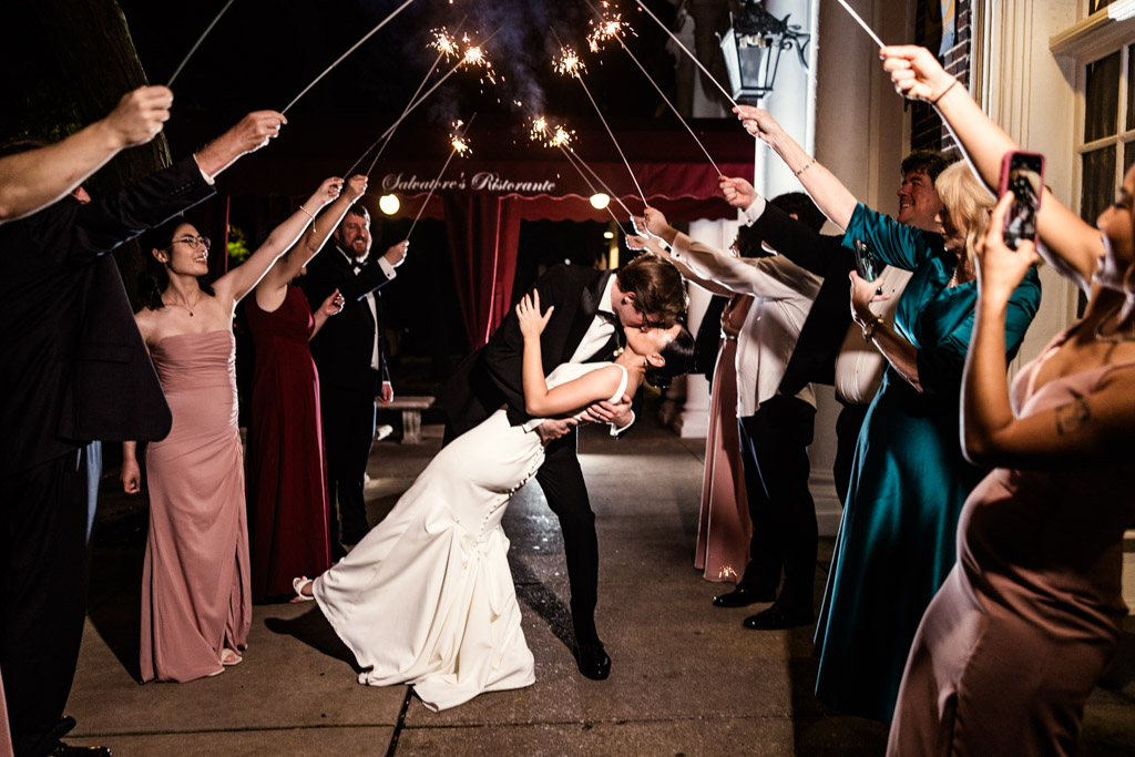 Newlywed couple kisses under sparklers held by guests in formal attire at a nighttime wedding celebration at Salvatore's Chicago