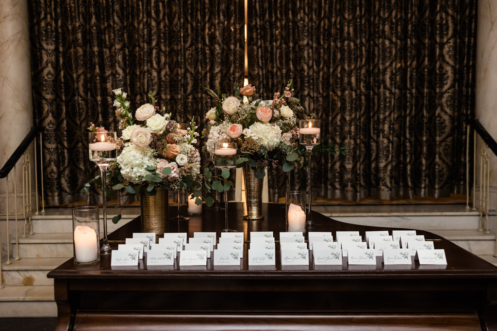 A table at Salvatore's with name cards, floral centerpieces, and candles set in front of dark patterned curtains