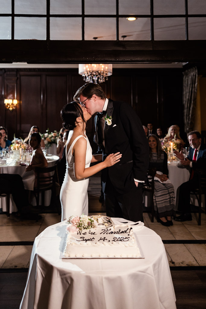 Bride and groom kiss after cutting their wedding cake during their Salvatore's reception